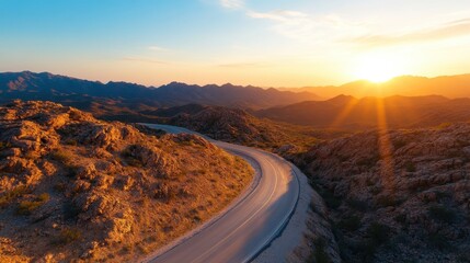 A stunning view of a curvy road meandering through rocky mountains bathed in golden hour light, creating a magical atmosphere that captivates the spirit of adventure.