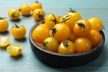 Many fresh yellow tomatoes on light blue wooden table, closeup