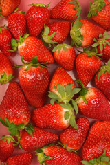 A close-up overhead view shows a pile of fresh, ripe red strawberries with green stems