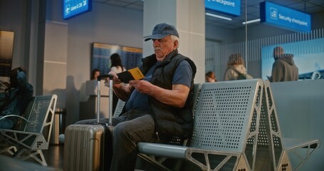 Crowded Airport Terminal: Senior Man with Suitcase and Passport Sitting in Departure Hall After...