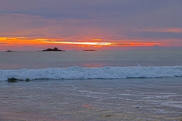 Sun setting over ocean at Ventura beach with soft waves and orange glow