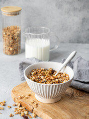 Homemade baked granola or muesli in a bowl on a wooden board on a light background