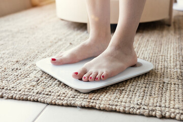 Young woman standing on scales at home, close up. Weight loss concept