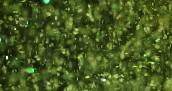 Green glittering particles fall creating sparkling texture. Ideal for festive projects celebrations and design needing touch of magic slow motion