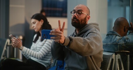 Crowded International Airport Terminal: Man Talking by Video Chat, Filming Video Content from Trip...