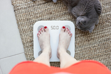 Young woman standing on scales at home, close up. Weight loss concept