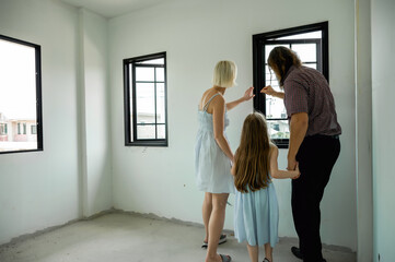 Family inspects their new home together, touching the window and imagining the future in their...