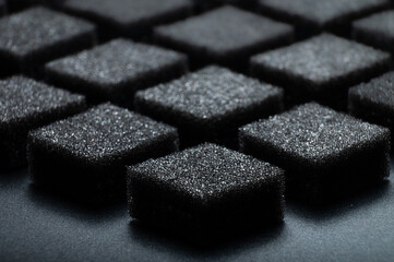 Black foam texture as background, side view. Sponge surface. Abstract black porous layers folded into a symmetrical pattern