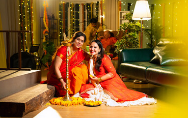 Working on rangoli design, Indian woman and mother celebrate Diwali in festive indoor setup