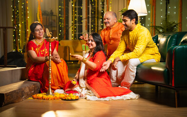 Lighting traditional samai indoors, Indian family gathers for festive Diwali celebration with joy