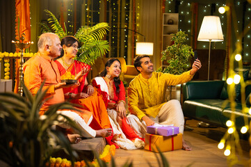 Indian family capturing Diwali memories indoors, surrounded by festive decor, smiles, and sweets
