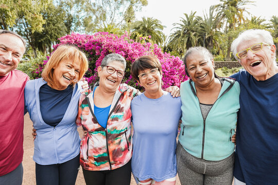 Multiracial senior people having fun after workout exercises outdoor with city park in background - Healthy lifestyle and joyful elderly concept - Main focus center faces - Powered by Adobe