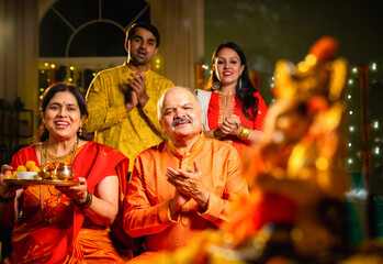 Indian family offering aarti to Ganpati idol at home with festive decor and traditional wear