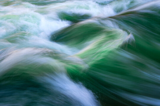 Colorful standing wave of the &ldquo;Eisbach&rdquo; creek in Munich (Germany). Popular attraction in the English Garden of the Bavarian capital. Motion blur due to long time exposure of powerful river current.