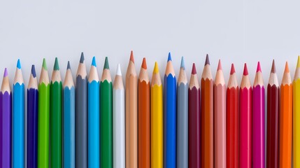 A row of colored pencils are lined up on a white background. The pencils are of various colors