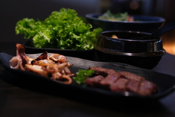 grilled squid pieces photo of mixed grilled meat platter. Beef, pork, poultry, sausages, grilled garlic, chili pepper, red tomatoes on wooden rustic background. High quality photo