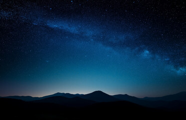 Dark starry night sky above peaceful mountains, enhanced with blue tones and soft light, creating a tranquil, dreamy background ideal for digital ads or product presentation visuals.