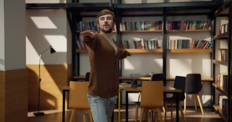Focused guy student stands in warrior pose during yoga class in library