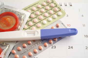 Pregnancy test and birth control pills on calendar, contraception health and medicine.