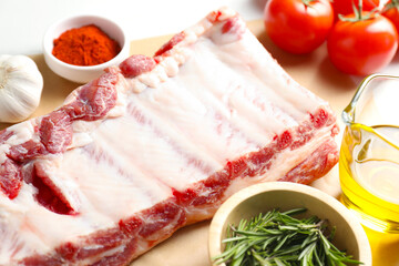 Raw pork ribs, spices and tomatoes on white table, closeup