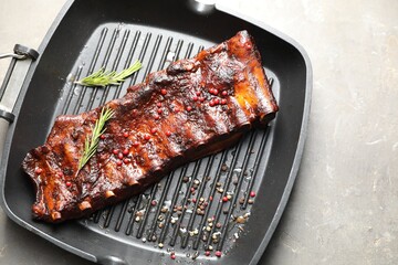 Delicious roasted pork ribs with rosemary on grey table, top view