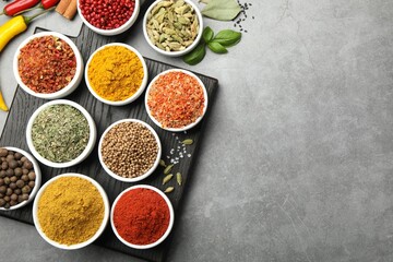 Different aromatic spices on grey table, flat lay. Space for text