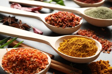 Many different spices in spoons on grey table, closeup