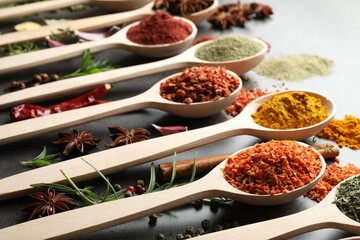 Many different spices in spoons on grey table, closeup
