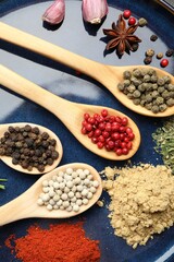 Different aromatic spices in spoons on plate, closeup