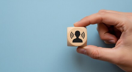 AI image hand holds a wooden block displaying a sound/listening icon, symbolizing communication, auditory perception, or customer feedback effectivel