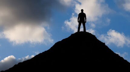 Silhouette of person standing atop a mountain peak against a dramatic sky.