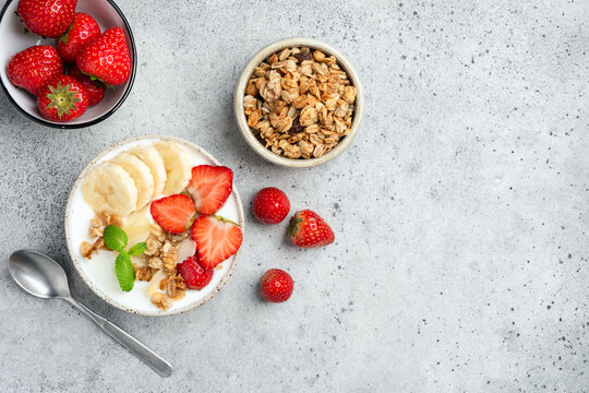 Healthy breakfast bowl with yogurt, granola and fruits on grey table, top view copy space - Powered by Adobe
