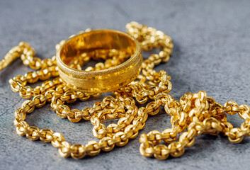 Gold price, gold jewelry, close-up of gold ring and gold necklace on grey background.