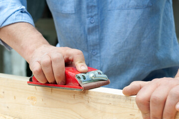 carpenter polishes the board with sandpaper closeup