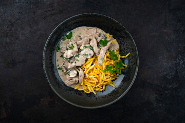 Traditional Swiss Zürcher geschnetzeltes from veal with mushrooms spaetzle in cream sauce served as top view in a design bowl