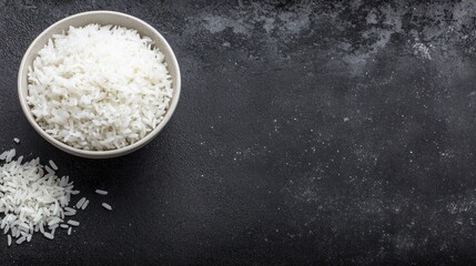 Cooked white rice in bowl dark background overhead view