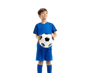 Confident boy in blue sport outfit posing with classic soccer ball over white background