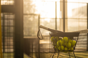 Folding basket with balls for padel classes on the court. Trainer equipment. Background with copy...