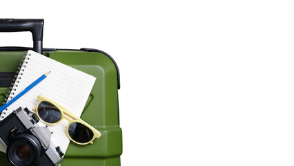A green suitcase with a notebook, a pencil, and a pair of sunglasses on top of it