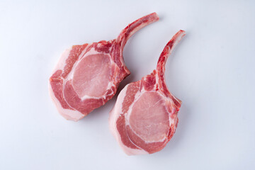Raw dry aged trimmed bone-in pork loin chops cutlets offered as top view on white background -...