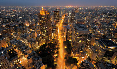 Obraz premium Nighttime cityscape with illuminated buildings and vibrant light trails