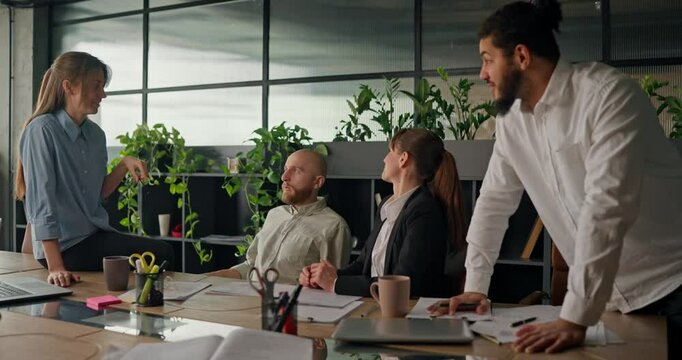 Office worker shares ideas and discusses projects with colleagues at the table engaging in casual conversation during a break from work