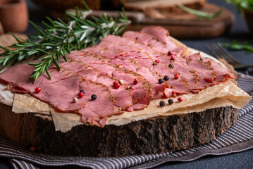 Sliced pastrami meat with rosemary and pepper