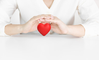Red Heart Being Protected by Two Gentle Hands on White Background