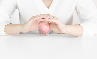 Female Hands Covering Pink Piggy Bank Symbolizing Financial Protection