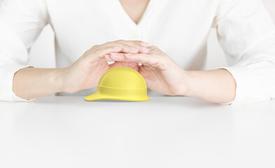 Protective Hands Above Yellow Hard Hat Representing Workplace Safety