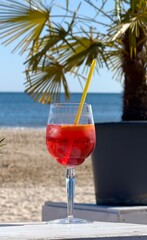 cocktail on the beach, glass with red fresh cocktail on the beach with palms