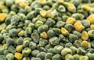 Close-up of frozen peas, showing many small, slightly uneven, green and yellow peas.  Frozen vegetable texture