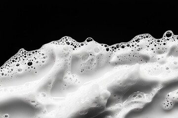 Close-up of frothy, white bubbles against a black background.  Dense, textured surface with various sized bubbles.  Abstract patterns form a wave-like shape