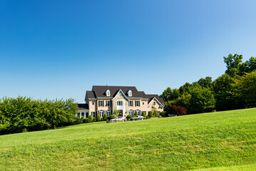 Obraz premium Large country house and summer landscape with a perfect lawn. Blue sky and white clouds.